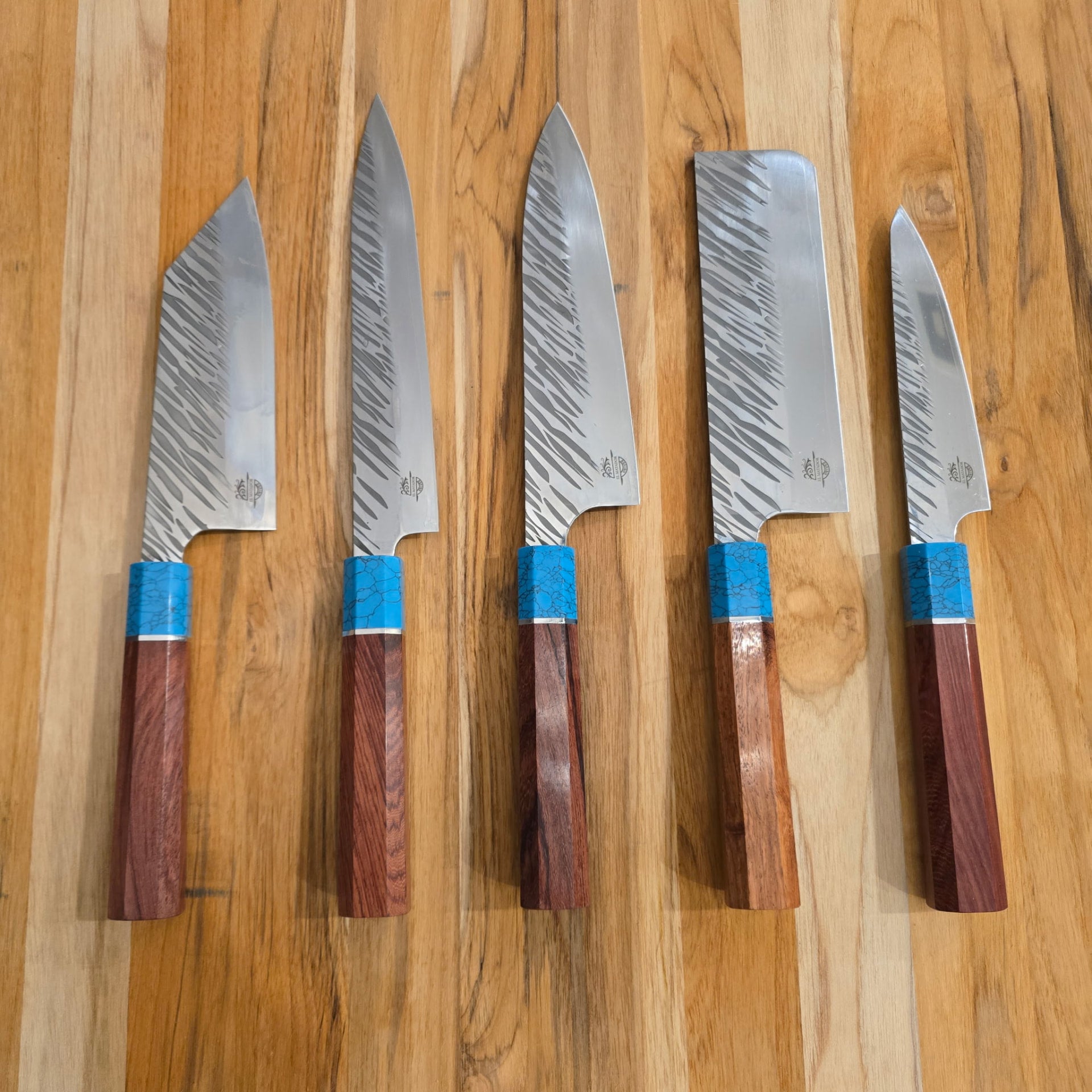 Five handcrafted El Matador knives with turquoise and wood handles arranged on a wooden cutting board
